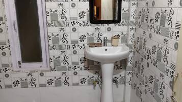 A bathroom with a white sink, a mirror, and patterned tiles on the walls and floor.