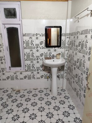 Un baño con un lavamanos blanco, un espejo y azulejos estampados en las paredes y el suelo.