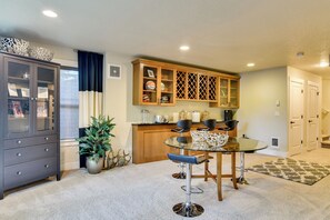A modern kitchen with a dining area, featuring a glass-top table, chairs, and a cabinet with glass doors. - 3BR Beaverton Home, Extended Retreat! (Beaverton)