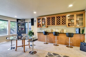 A modern kitchen with a glass dining table, bar stools, and wooden cabinets. - 3BR Beaverton Home, Extended Retreat! (Beaverton)