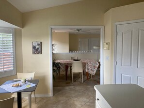 Une pièce comprenant une table à manger, des chaises, un ventilateur de plafond et une porte.