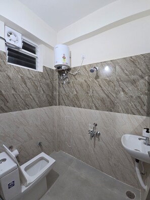 A bathroom with a toilet, sink, shower, and a water heater. - Manzl Collective Peepal  (Tada)