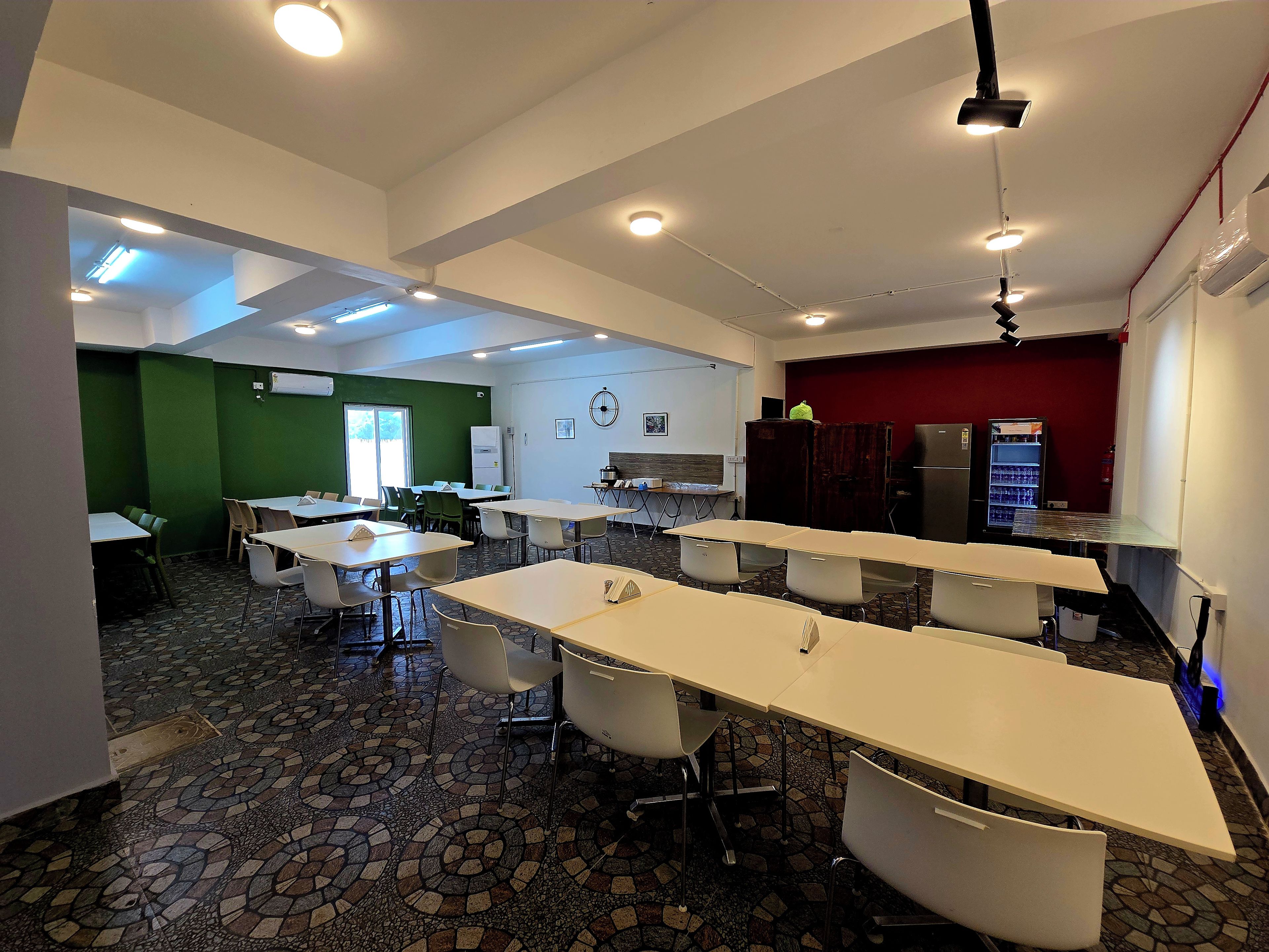 A conference room with tables and chairs, a whiteboard, and a refrigerator.