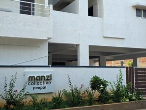 Un edifici amb un cartell que diu 'manzi collective peepal' i una entrada tancada amb una barrera de formigó.