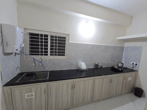 A kitchen with a black countertop, wooden cabinets, a window with a grid pattern, and a water heater.