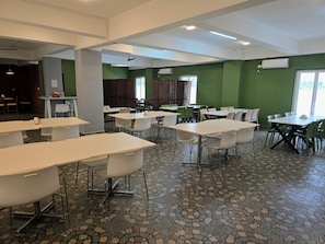 A spacious indoor area with multiple tables and chairs, a patterned floor, and green walls.