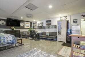 A modern living room with a flat-screen TV, a sofa, a dining table, and a kitchen area with a refrigerator and water dispenser. - Chicago South Side Studio w/ Gated Parking (Chicago)
