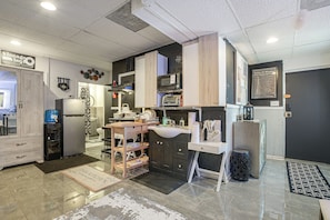 A modern kitchen with a refrigerator, microwave, and stove. There is a wooden island with a sink and a small stool. The kitchen has a black and white color scheme with a gray backsplash. - Chicago South Side Studio w/ Gated Parking (Chicago)