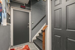 Ein Flur mit einer geschlossenen Tür, einer Treppe und einem roten Teppich mit Muster.