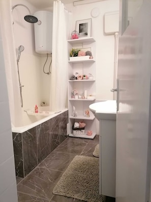A bathroom with a shower, a bathtub, a white sink, and a shelf with toiletries. - Apartment Jamblip - Two Bedroom Apartment With Balcony (Split)