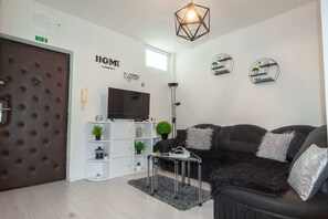 A modern living room with a sofa, a TV, a bookshelf, and decorative wall art. - Apartment Jamblip - Two Bedroom Apartment With Balcony (Split)
