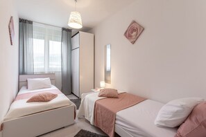 A modern bedroom with two beds, a large window, and a mirror. - Apartment Jamblip - Two Bedroom Apartment With Balcony (Split)