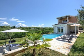 A two-story house with a swimming pool, outdoor furniture, and a view of the surrounding greenery. - Terracotta Hillside Hideaway Vranje (Vizinada)