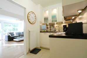 Uma cozinha moderna com armários brancos, bancada preta e um relógio de parede.