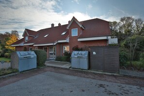 Ein zweistöckiges Backsteinhaus mit rotem Ziegeldach, Hauseingang und Auffahrt.