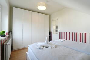 Ein Hotelzimmer mit einem Bett, einem Kleiderschrank, einer Heizung, einer Topfpflanze und einem Spiegel.