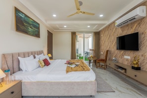 A modern bedroom with a bed, bedside table, and a television mounted on the wall. - ELIVAAS Signature Aura Sky 3 BHK Apt (Jaipur)