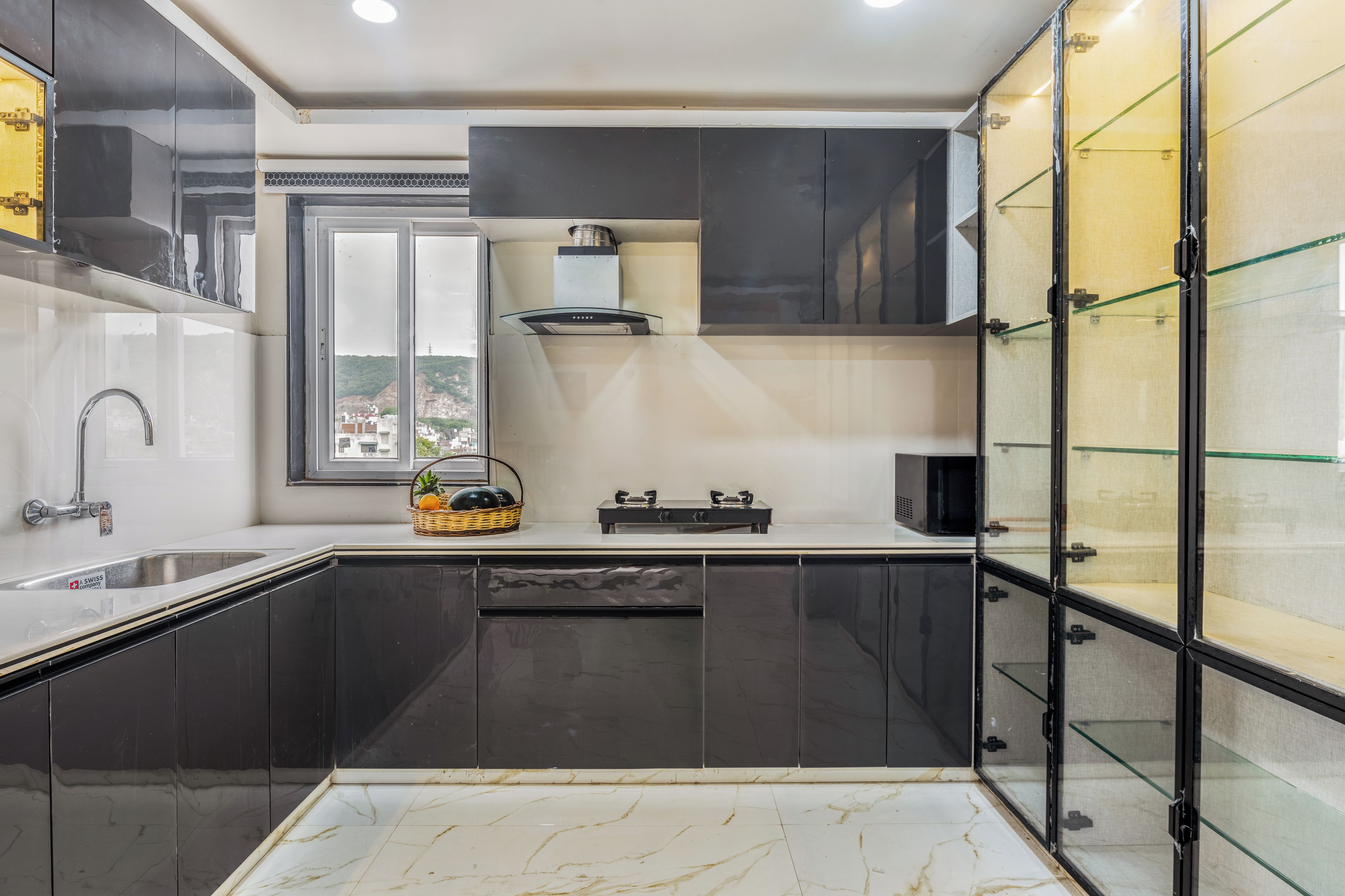 A modern kitchen with dark cabinetry, a stainless steel sink, and a window overlooking a cityscape.