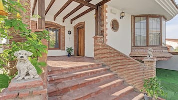 A building with a brick exterior, wooden beams, and a staircase leading to a door.