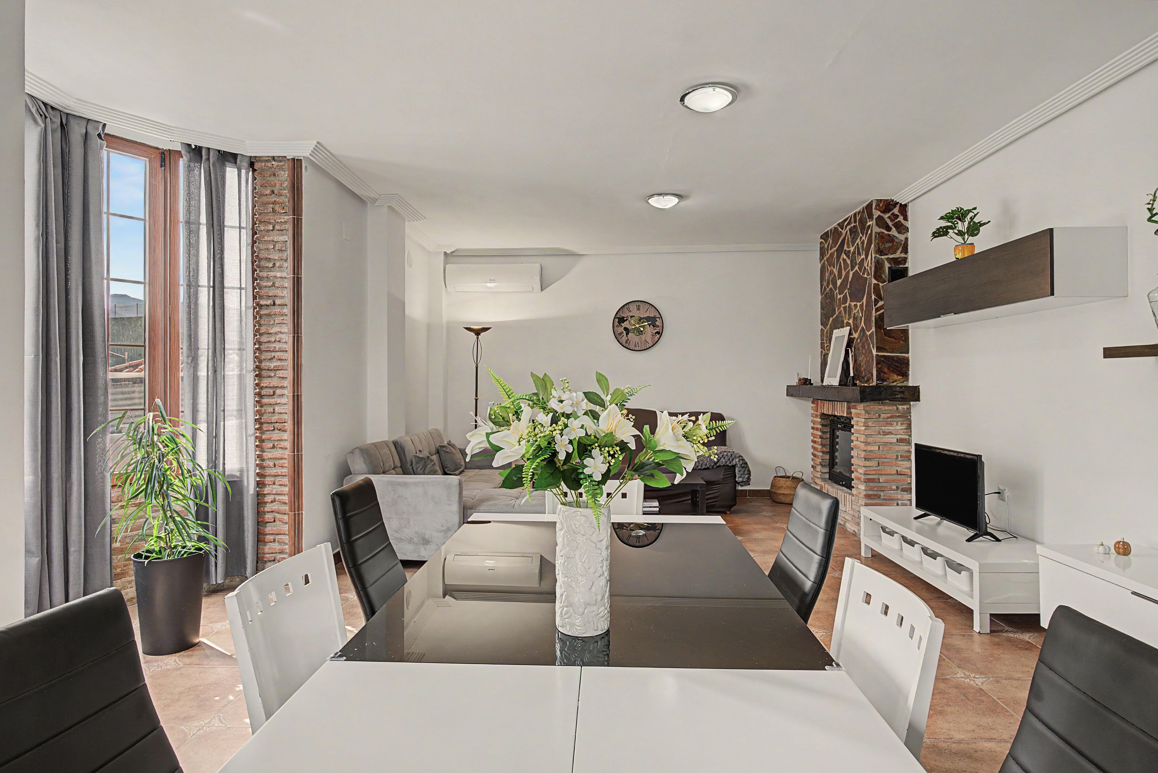 A modern living room with a dining area, a fireplace, and a TV.