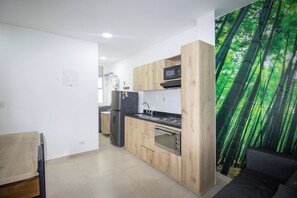 A modern kitchen with wooden cabinets, a microwave, a stove, and a refrigerator. - 42 Near the Athanasius and stadium station (Medellín)