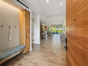 A modern interior with a wooden bench, a kitchen area, and a view of the outdoors. - Spacious Ground-Level Villa Near Pool, Beachfront Resort Amenities (Lahaina)