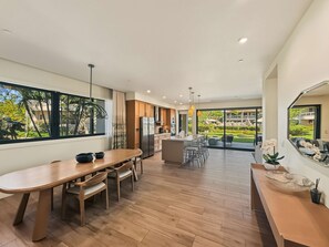 A modern kitchen with a central island, wooden flooring, and large windows offering a view of the outdoors. - Spacious Ground-Level Villa Near Pool, Beachfront Resort Amenities (Lahaina)