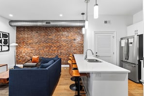 Una cocina moderna con pared de ladrillo, un sofá y una barra.