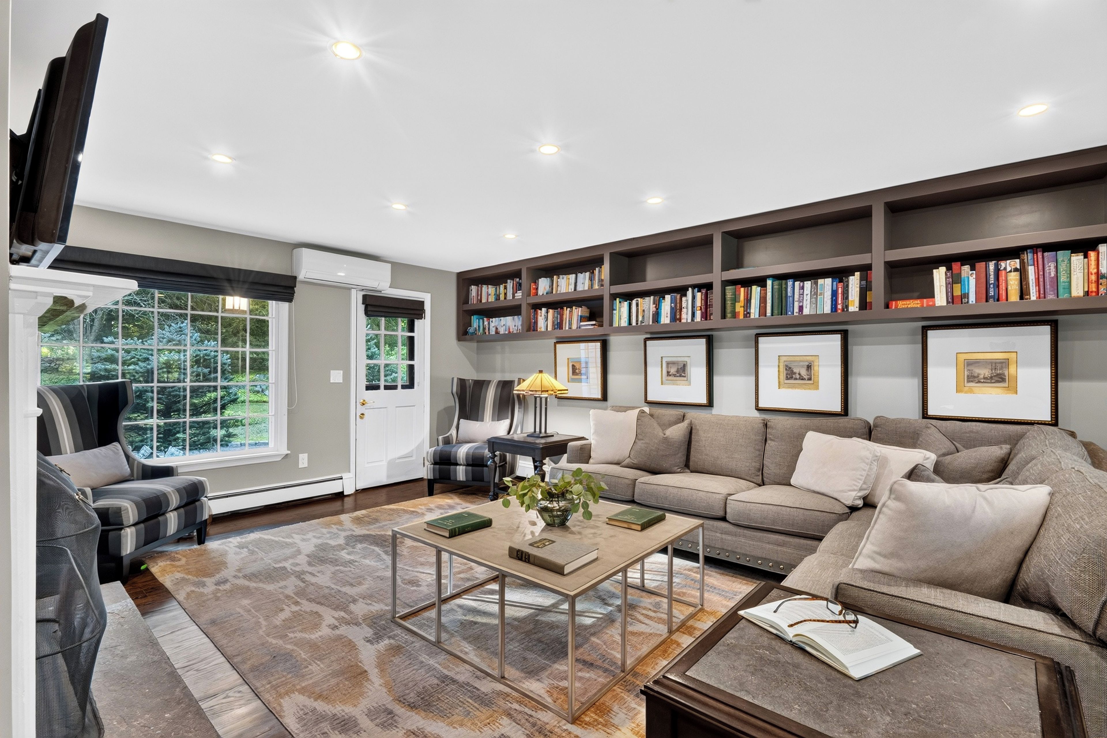 A modern living room with a sofa, armchairs, a coffee table, and a bookshelf filled with books.