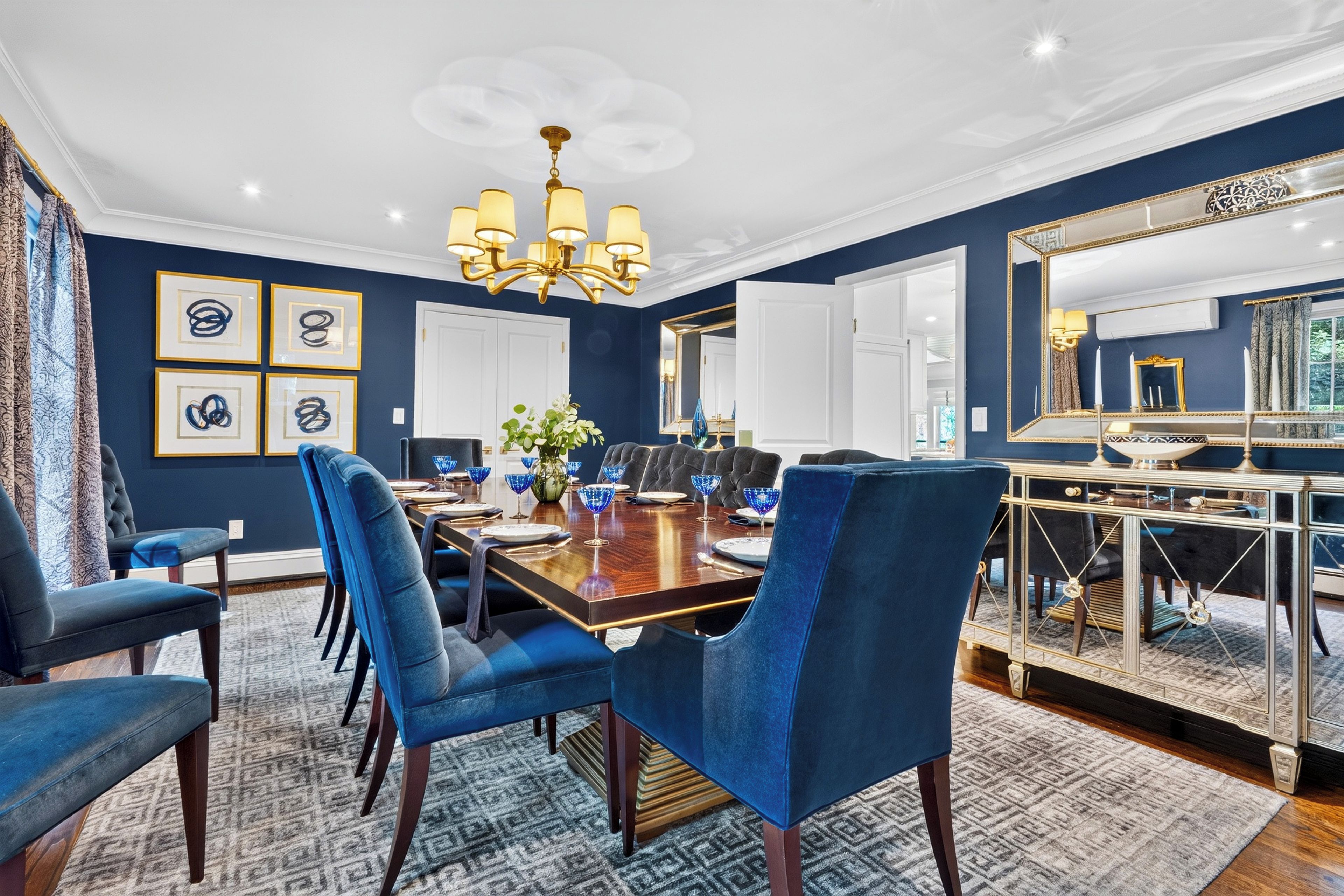 A dining area with a wooden table, blue upholstered chairs, and a chandelier.