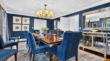 A dining area with a wooden table, blue upholstered chairs, and a chandelier.