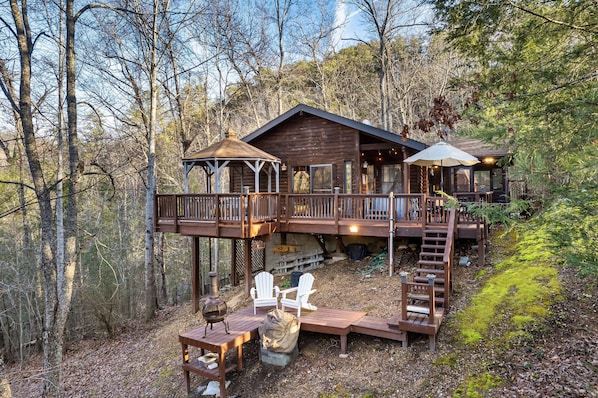 Eine Hütte mit einer Terrasse, Sitzgelegenheiten im Freien und einem überdachten Bereich.