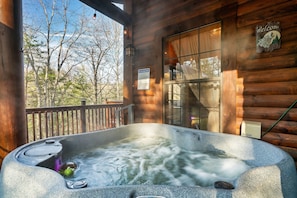 Ein Whirlpool mit Holzterrasse und Blick auf Bäume.