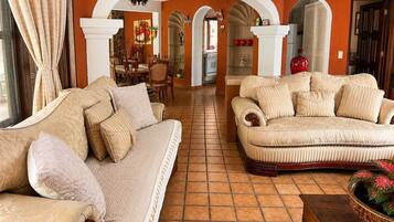 A living room with two sofas, a dining area, and a kitchen visible through an archway.