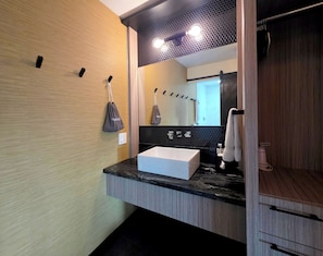 Un baño moderno con un espejo grande, un lavabo blanco y un perchero para toallas.