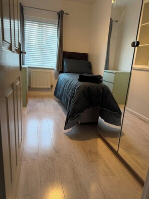 A bedroom with a bed, a radiator, a window with curtains, and a wardrobe. - A&R Guest House - 2-Bed Coach House, Bristol (Bradley Stoke)