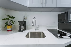 A modern kitchen with a stainless steel sink, a coffee maker, and a plant. - Chic North Miami Studio - 6 Mi to Beach! (North Miami)