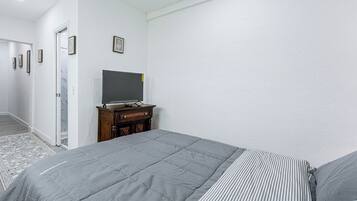 A bedroom with a bed, a dresser, and a television on a stand.