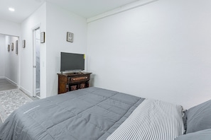 A bedroom with a bed, a dresser, and a television on a stand. - Chic North Miami Studio - 6 Mi to Beach! (North Miami)