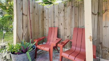 A wooden fence with two red plastic chairs and a potted plant.