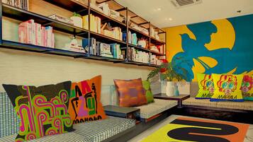 A modern interior with a bookshelf, colorful cushions, and a vibrant wall mural.