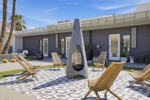 An outdoor seating area with lounge chairs and a central fire feature. - Pool + Spa + Firepit + Courtyard | Mtn Views | Sun Queen at Mahala (Palm Springs)