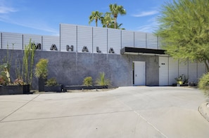 A building with the name 'MAHALA' on the facade, a concrete entrance, and a parking area. - Pool + Spa + Firepit + Courtyard | Mtn Views | Sun Queen at Mahala (Palm Springs)