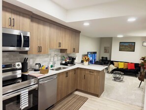 A modern kitchen with stainless steel appliances, wooden cabinets, and a central island. - Private Suite Near Calgary Airport (Calgary)
