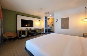 Una habitación de hotel con una cama grande, un escritorio, un televisor de pantalla plana, una silla y un armario.