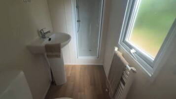 Un baño pequeño con lavabo, una toalla, ducha y ventana.