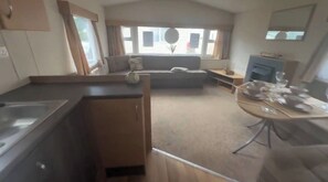 A compact living space with a kitchenette, a sofa, and a dining table. - 3 bed static caravan with 5 beds on a holiday park (Suffolk)