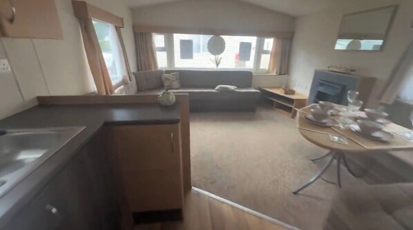 Un espacio habitable compacto con kitchenette, un sofá y una mesa de comedor.
