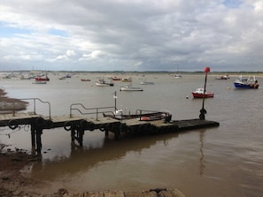 A pier with boats docked, a sandy shore, and a cloudy sky.