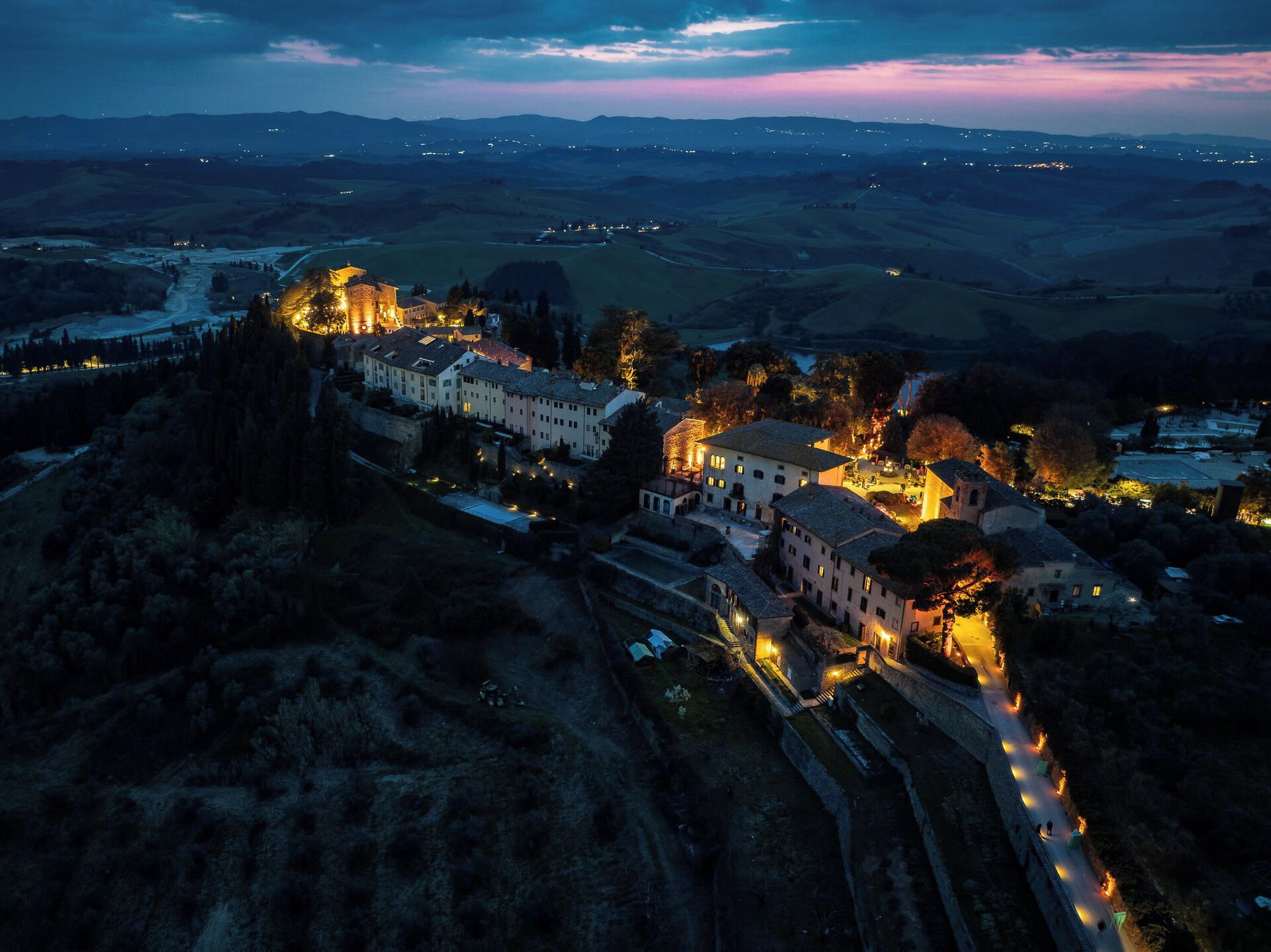 A historic town with medieval architecture, including a castle and traditional buildings, surrounded by rolling hills and a river.